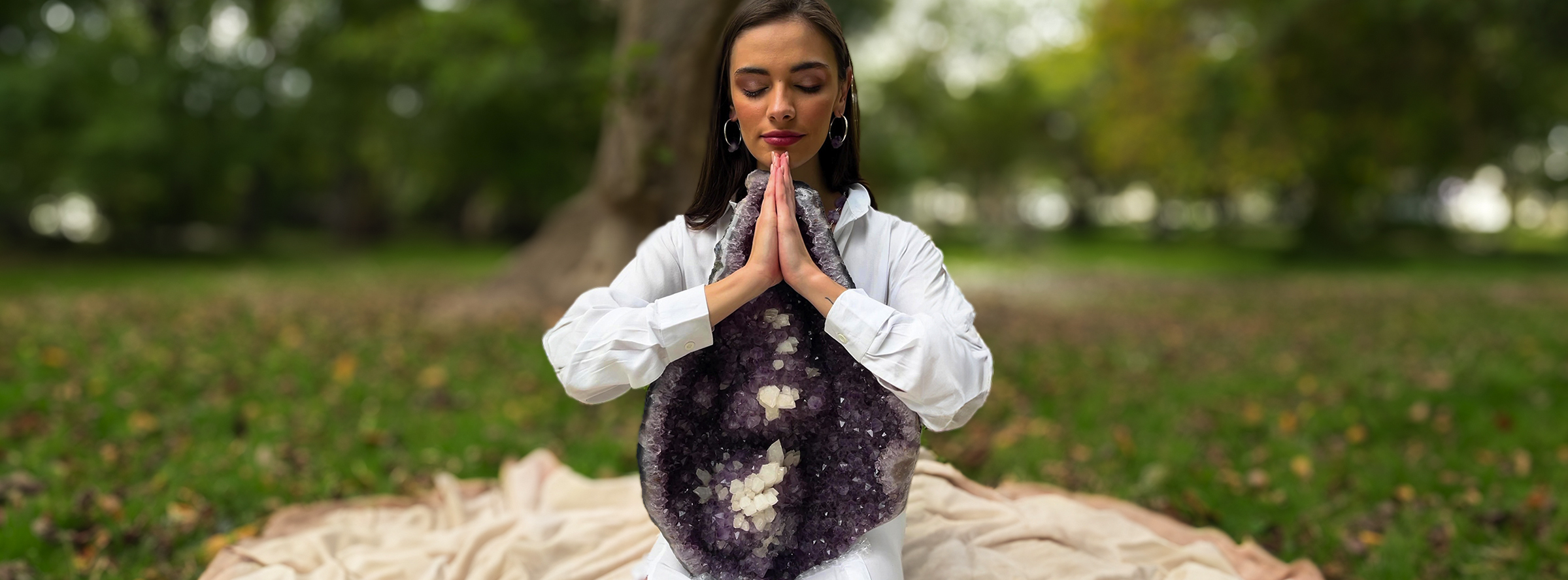Mujer juntando las manos y dando un abrazo a una drusa de amatista grande en la naturaleza