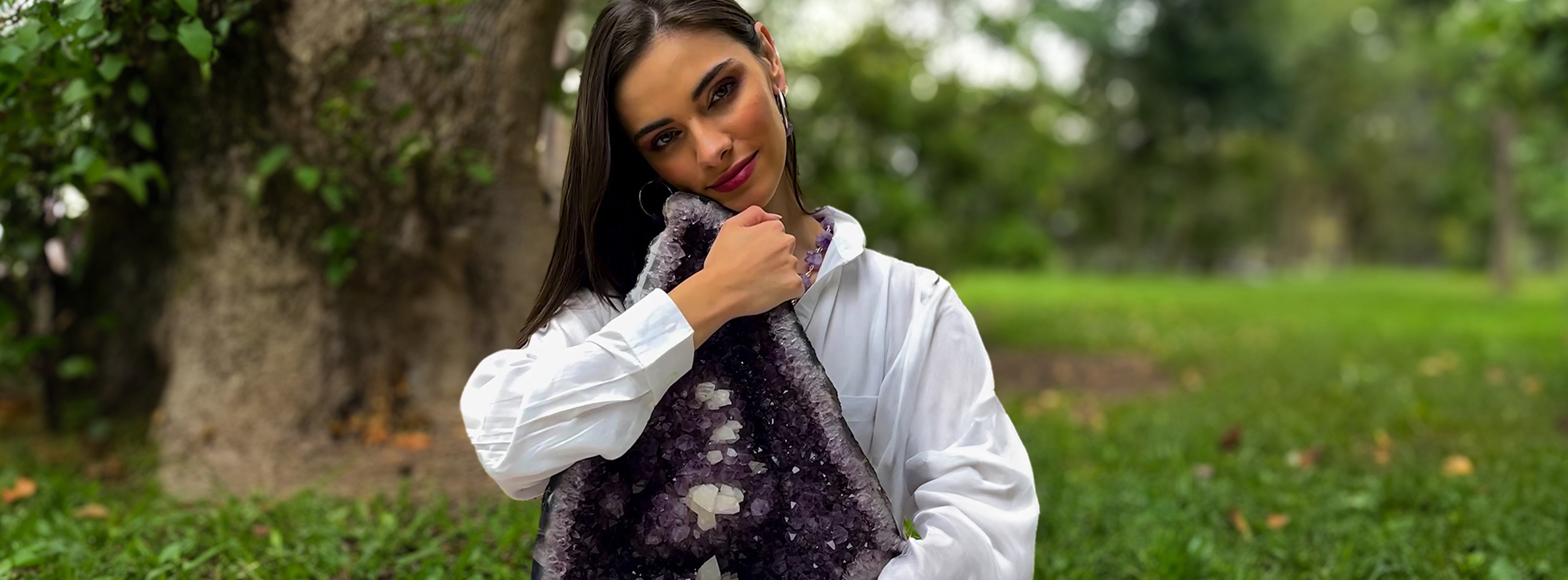 Mujer dando un abrazo a una drusa de amatista grande en la naturaleza